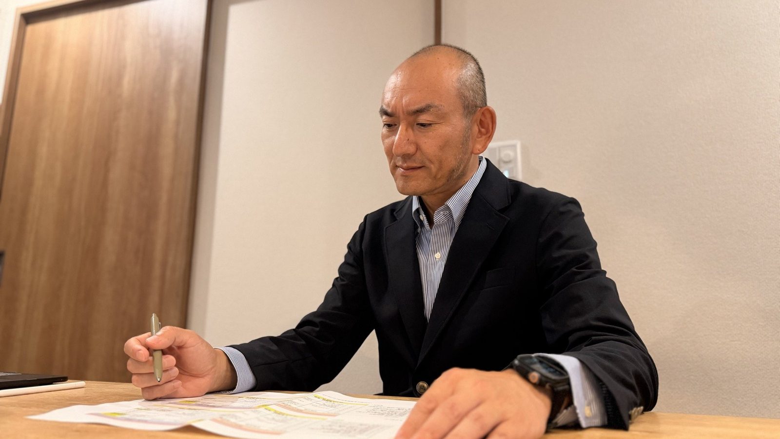 机に広げた書類に、ペンで印をつけているところ